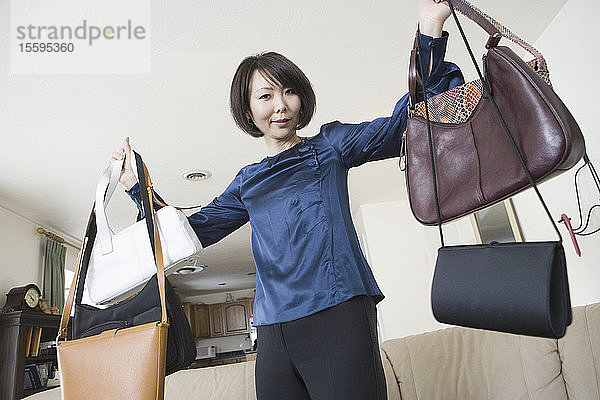 Porträt einer mittleren erwachsenen Frau  die ihre Handtaschen zeigt