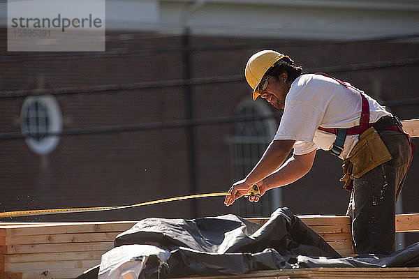 Zimmermann mit einem Maßband auf einer Baustelle