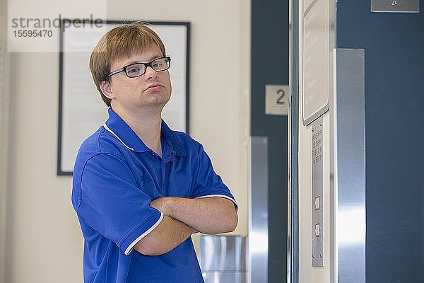 Junger Mann mit Down-Syndrom benutzt den Aufzug bei der Arbeit in einer Klinik