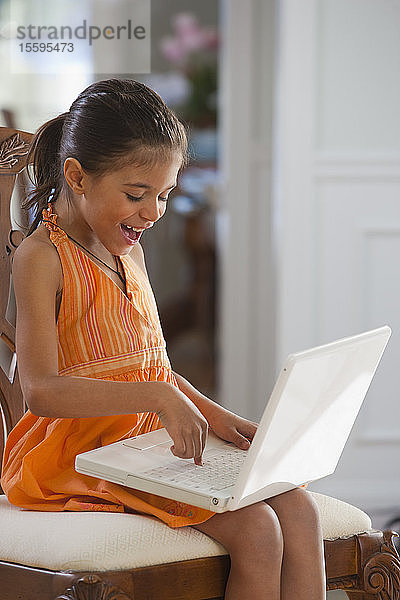 Hispanisches Mädchen arbeitet an einem Laptop und lächelt