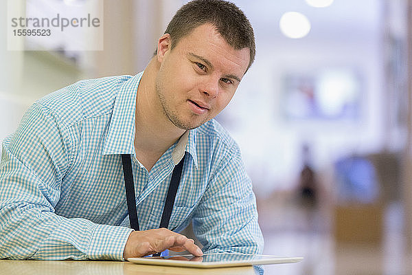 Junger Mann mit Down-Syndrom arbeitet als Krankenhaushelfer mit seinem Tablet