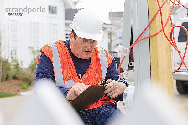 Bauingenieur mit Querschnittslähmung macht sich Notizen an einer provisorischen Versorgungsbox