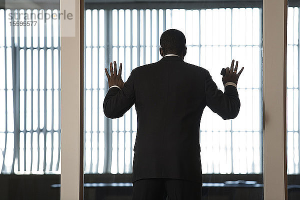 Ein Geschäftsmann schaut durch eine Glaswand in einem Büro.