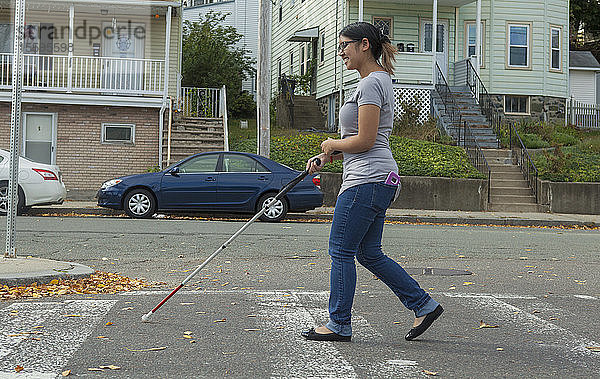 Frau mit Sehbehinderung geht mit ihrem Stock auf der Straße