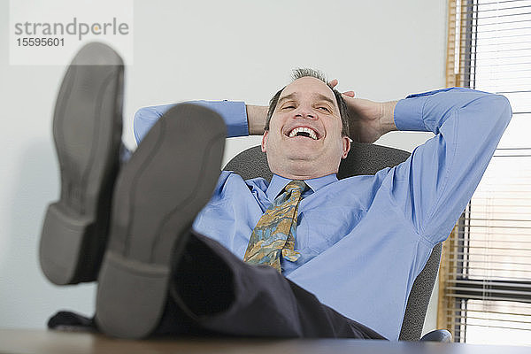 Geschäftsmann  der sich auf einem Stuhl ausruht und lächelt