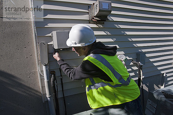 Kabeltechniker bei der Installation von Geräten an der Seite eines Hauses