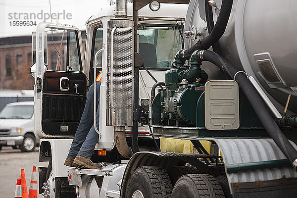 Umwelttechniker greift in die Fahrerseite eines Tankwagens  um gefährliche Abfälle zu beseitigen