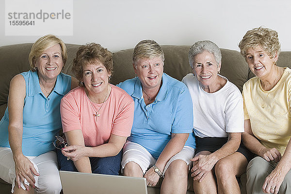 Porträt einer Gruppe von Frauen mittleren Alters  die zusammen auf einer Couch sitzen und lächeln