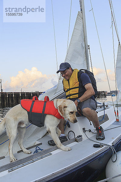 Mann mit Sehbehinderung und sein Diensthund beim Segeln