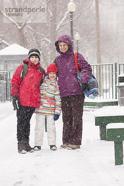 Mutter mit ihrer Tochter und ihrem Sohn bei Schneefall im Park