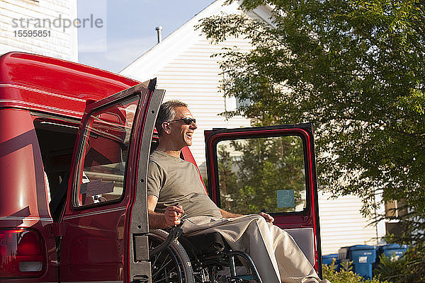 Mann im Rollstuhl mit Rückenmarksverletzung wird aus einem zugänglichen Transporter heruntergelassen