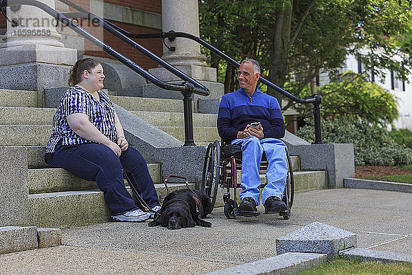 Mann mit Rückenmarksverletzung sitzt neben seiner blinden Tochter