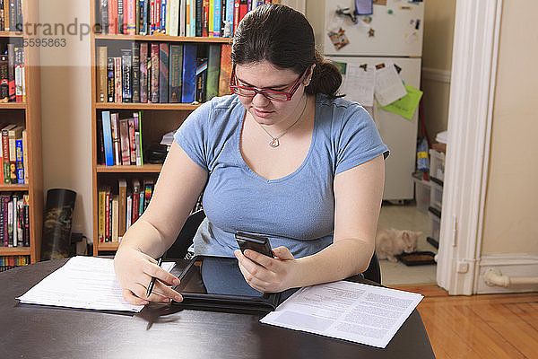 Frau mit Asperger-Syndrom arbeitet mit ihrem Smartphone und Tablet im Heimbüro