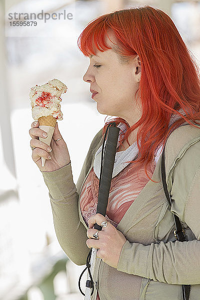 Junge blinde Frau mit Blindenstock genießt Eiscreme