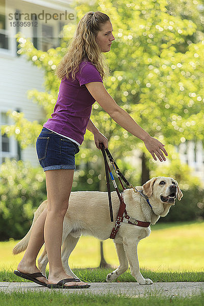 Frau mit Sehbehinderung weist ihren Diensthund an  abzubiegen