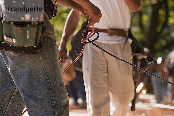 Zimmermann entwirrt Stromkabel auf einer Baustelle