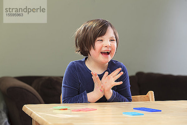 Kleines Mädchen mit Down-Syndrom spielt ein Lernspiel und lächelt