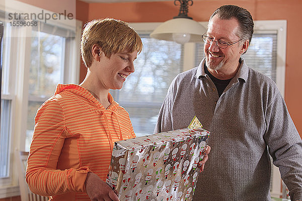 Junge Frau mit Sehbehinderung sieht sich mit ihrem Vater ein Weihnachtsgeschenk an