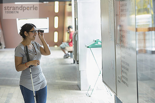 Frau mit Sehbehinderung benutzt ihren Stock und liest