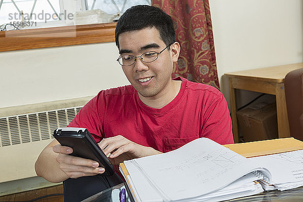 Glücklicher asiatischer Mann mit Autismus  der ein Telefon benutzt