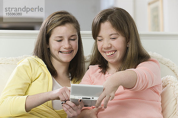 Zwei Teenager-Mädchen spielen ein Handheld-Videospiel  eines mit Geburtsfehler