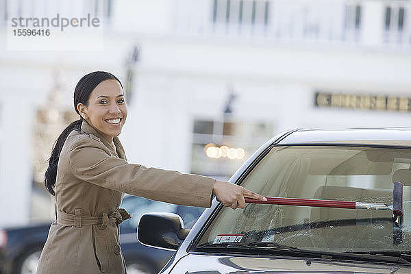 Hispanische Frau wäscht die Windschutzscheibe eines Autos