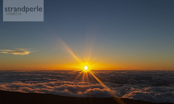 Haleakala bei Sonnenuntergang mit dramatischen goldenen Sonnenstrahlen leuchten hell über Wolken; Maui  Hawaii  Vereinigte Staaten von Amerika