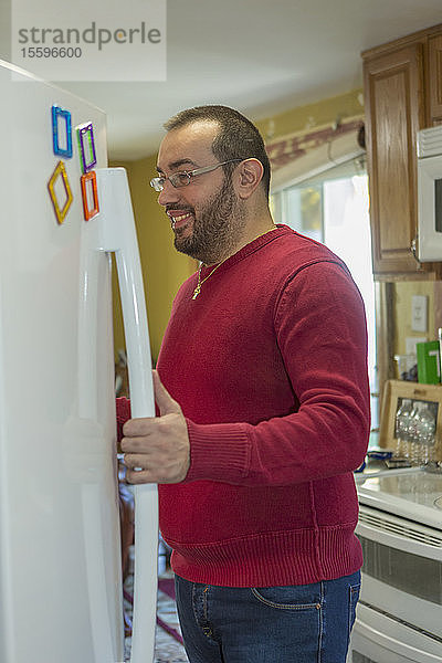Mann mit Sehbehinderung öffnet Kühlschrank