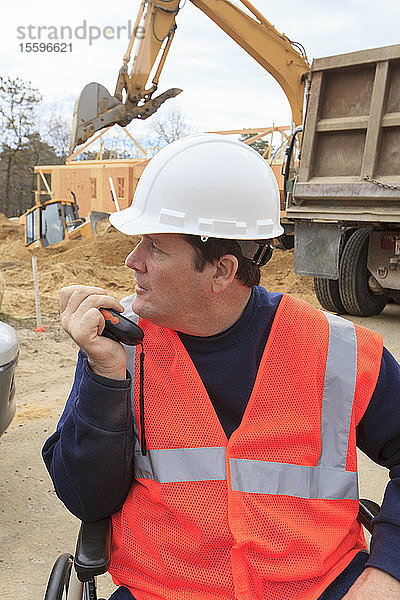 Ein Bauingenieur mit einer Rückenmarksverletzung spricht über ein tragbares Funkgerät mit den Maschinisten