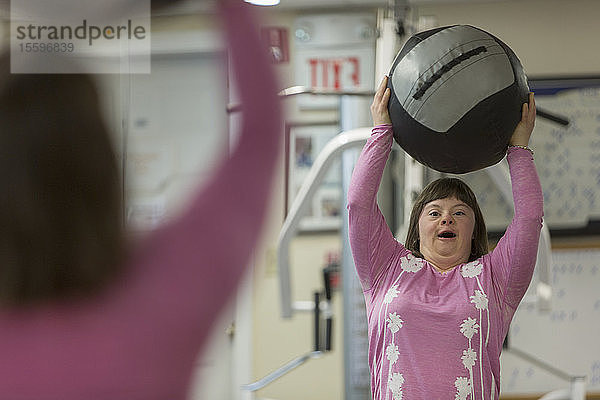 Mädchen mit Down-Syndrom trainiert mit einem Gymnastikball