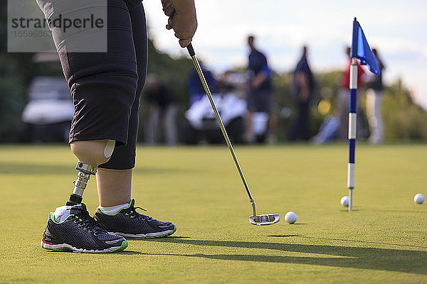 Frau mit Beinprothese beim Golf-Putting-Green