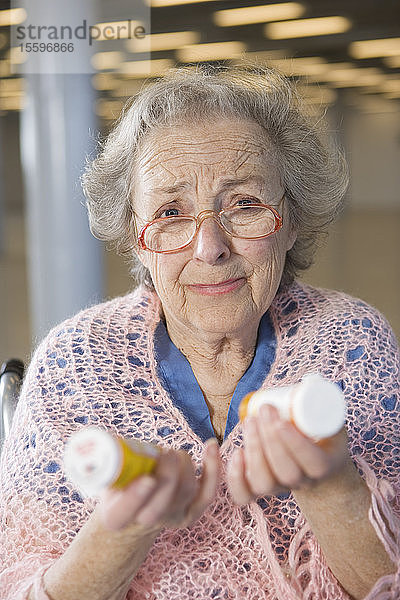 Blick auf eine ältere Frau  die Medikamente in den Händen hält.