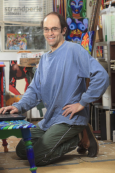 Mann mit Asperger-Syndrom bei der Arbeit an seinem Computer in seinem Kunstatelier