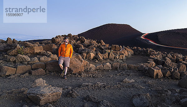 Mann  der auf schroffen Felsen über den Wolken auf dem Haleakala steht; Maui  Hawaii  Vereinigte Staaten von Amerika