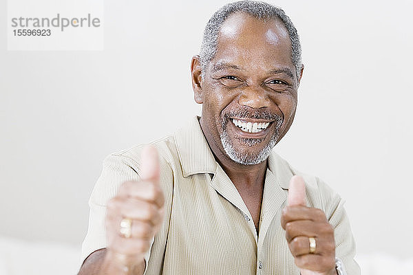 Porträt eines Mannes mittleren Alters  der lächelnd einen Daumen nach oben zeigt