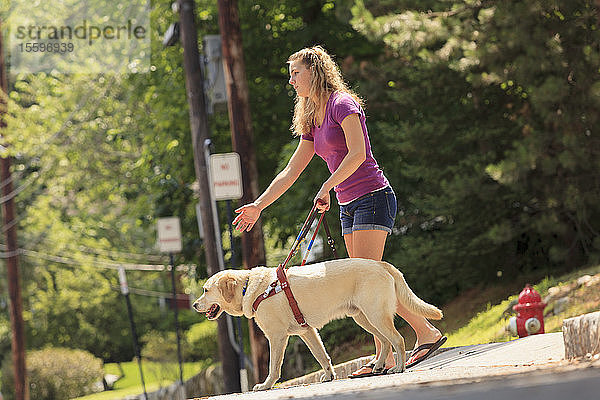 Studentin mit Sehbehinderung weist ihren Diensthund an  sich umzudrehen