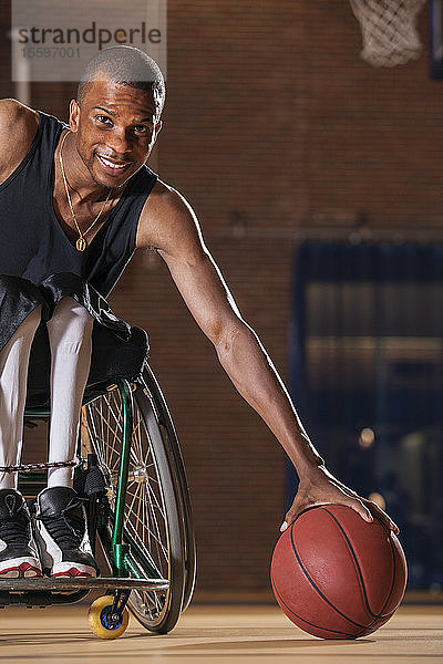 Mann mit Spinaler Meningitis hebt im Rollstuhl einen Basketball auf