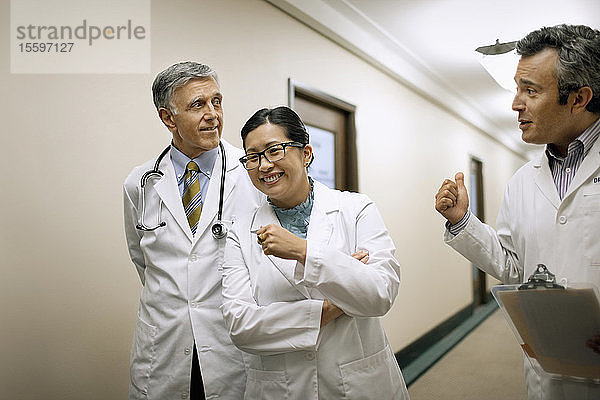 Lachende und sich unterhaltende Ärztekollegen auf dem Flur eines Krankenhauses