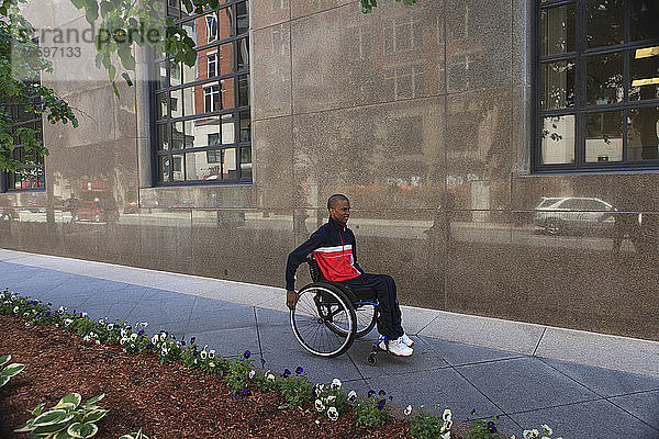 Mann im Rollstuhl  der an Spinaler Meningitis erkrankt war  benutzt einen städtischen Gehweg