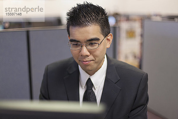 Asiatischer Mann mit Autismus arbeitet am Computer in einem Büro
