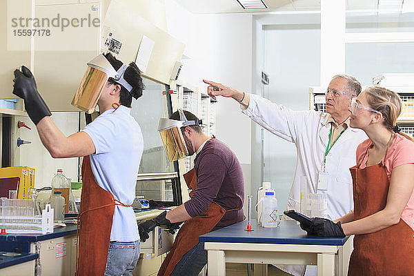 Ingenieurstudenten und Professor tragen Schutzausrüstung bei der Arbeit im Chemielabor