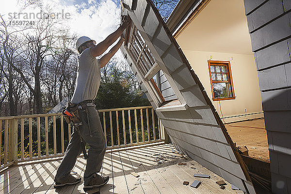 Hispanischer Schreiner beim Entfernen der neu geschnittenen Tür zum Deck eines Hauses