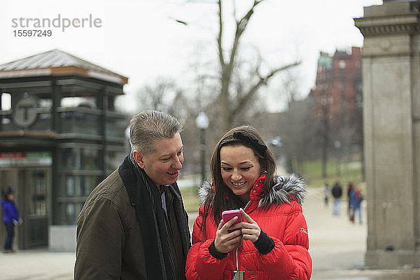 Ein Paar schaut auf ein Handy in der Tremont Street in der Nähe der U-Bahn-Station  Boston  Suffolk County  Massachusetts  USA