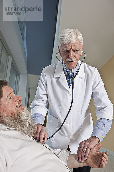Arzt  der einen Patienten mit einem Stethoskop untersucht  der Patient ist bipolar