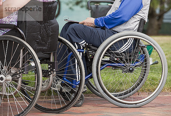 Ein Mann mit Multipler Sklerose und eine Frau mit Rückenmarksverletzung in Rollstühlen