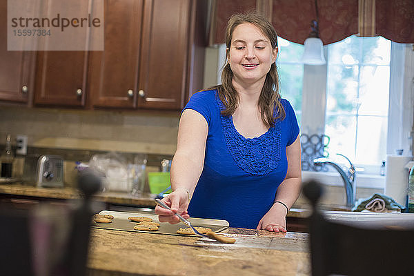 Junge Frau mit zerebraler Lähmung legt Kekse auf ein Tablett