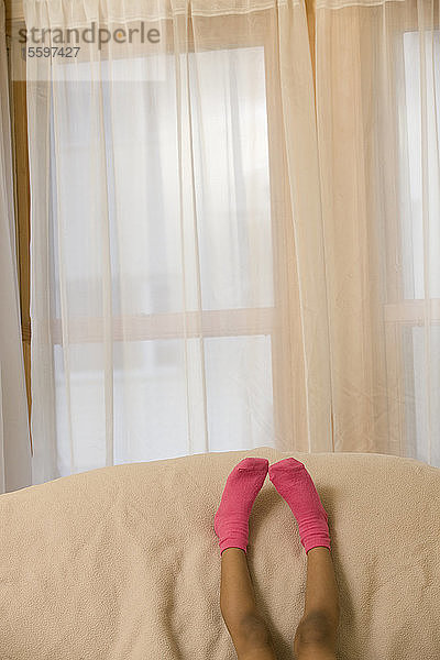 Hispanisches Mädchen  das sich mit hochgelegten Füßen auf einer Couch ausruht