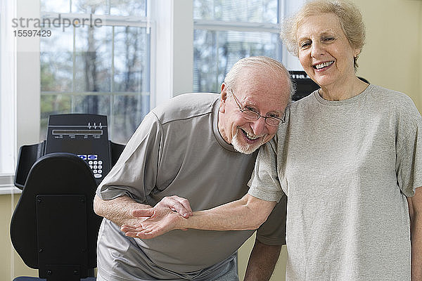Ein älteres Paar lächelt und prüft den Puls in der Turnhalle.