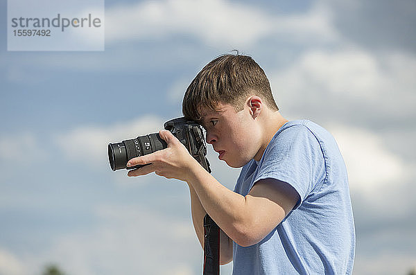 Junger Mann mit Down-Syndrom beim Fotografieren mit Kamera