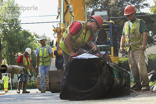 Bauarbeiter schneiden die Wasserleitung mit einer gasbetriebenen Säge auf Länge